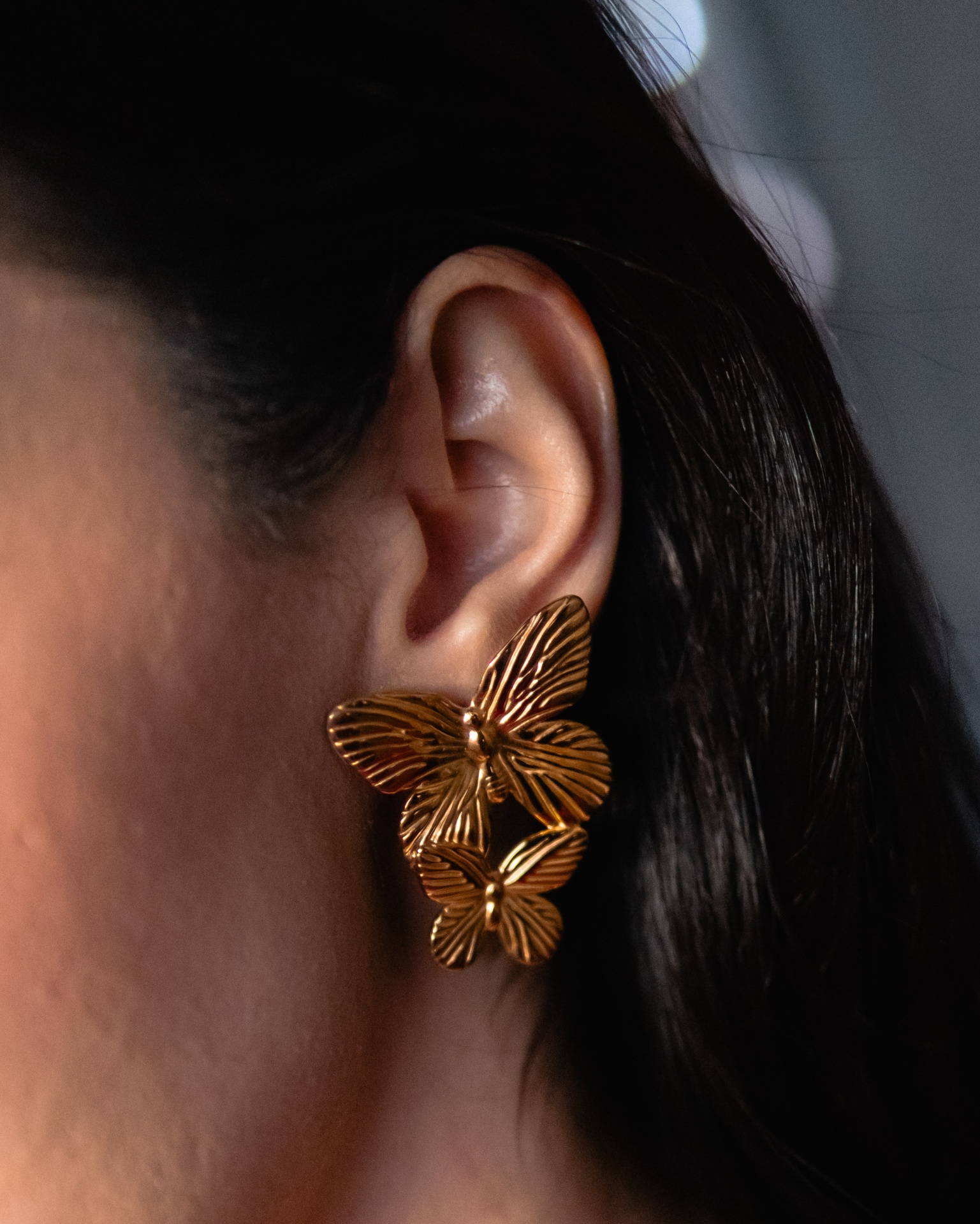 Brincos dourados com borboletas em orelha feminina