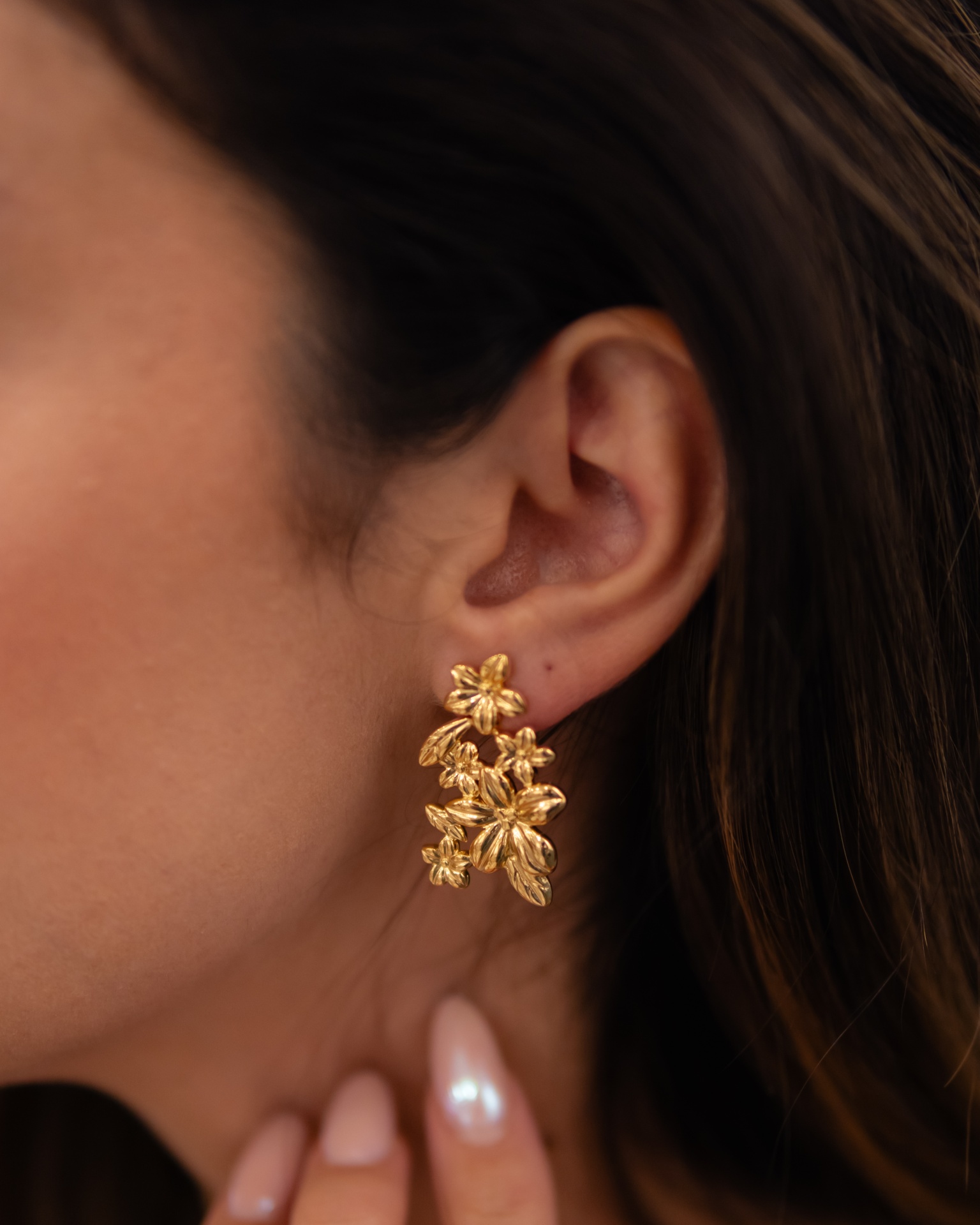 Brincos dourados em forma de flores e folhas com textura detalhada