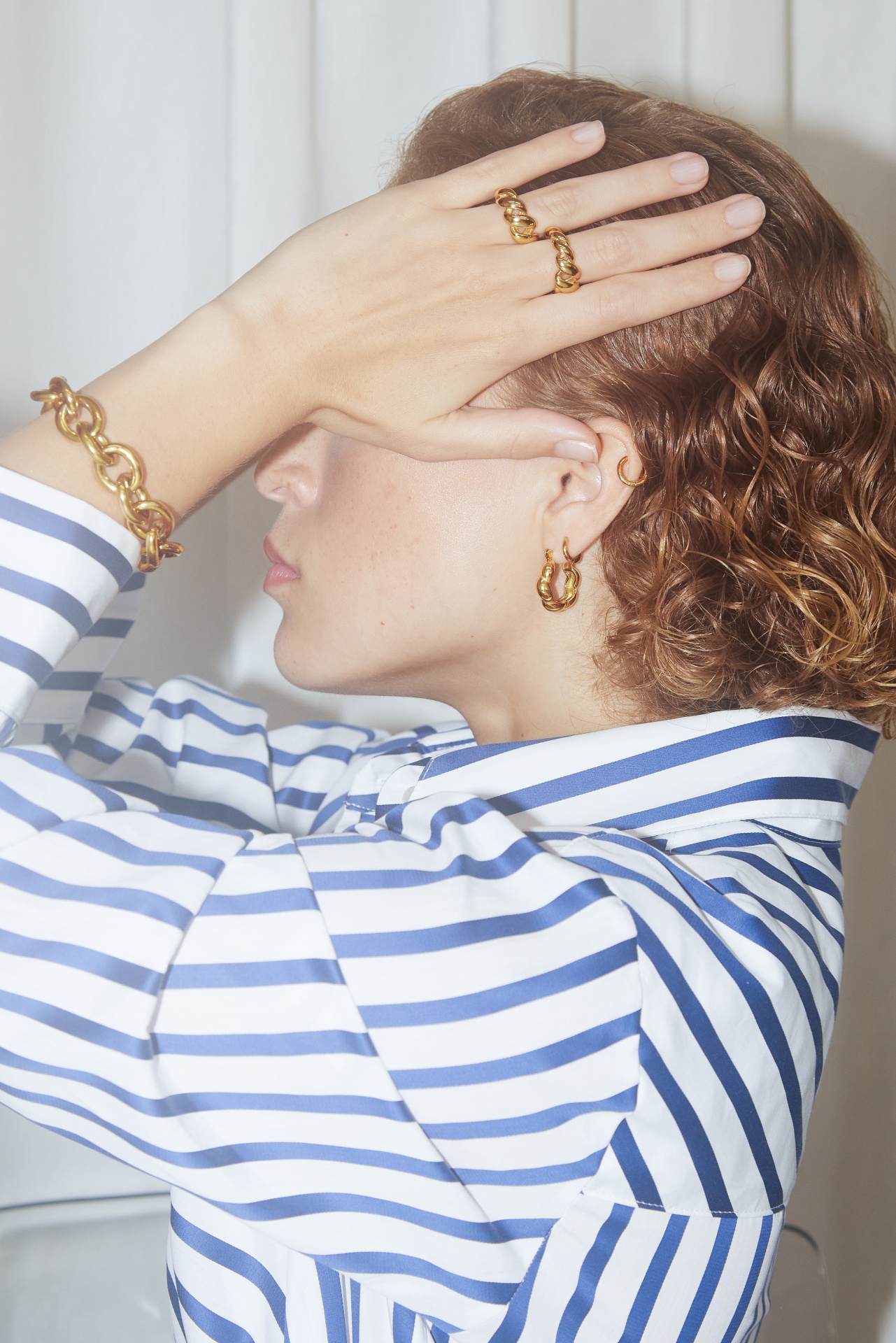 Pessoa com camisa às riscas azul e branca e joias douradas