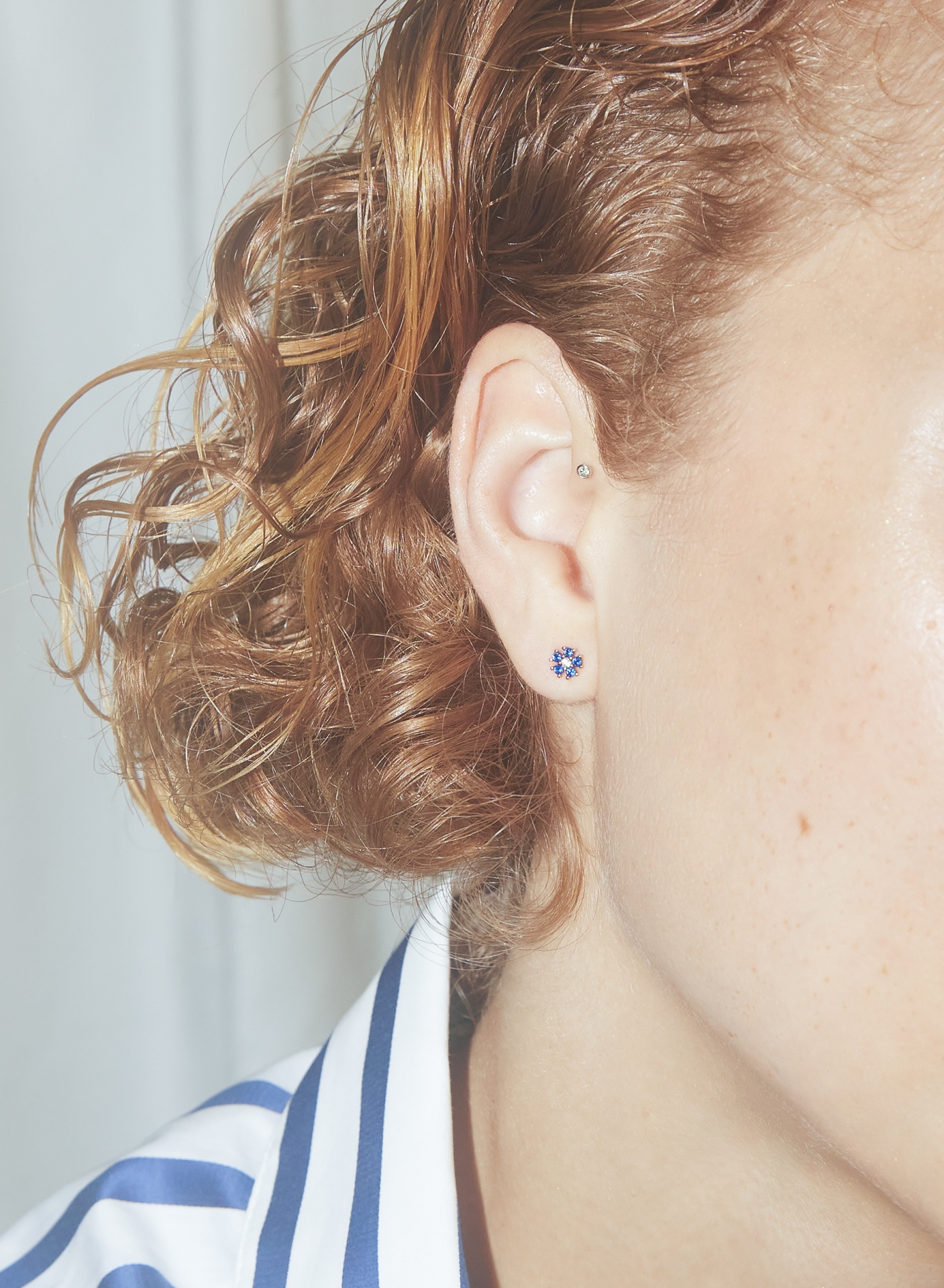 Brinco de pérola azul com cristais brilhantes em orelha feminina com cabelo ruivo encaracolado