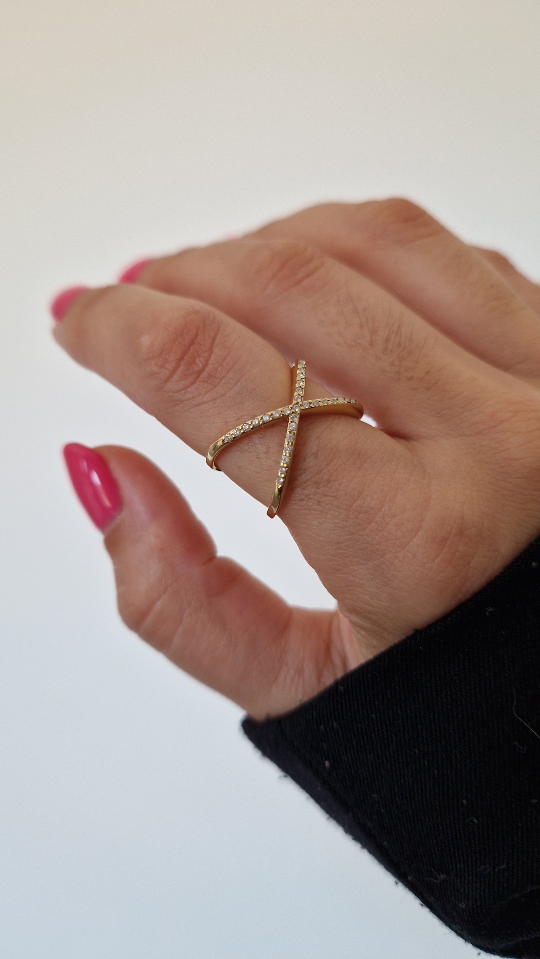 anel dourado com pedras brilhantes em forma de cruz no dedo