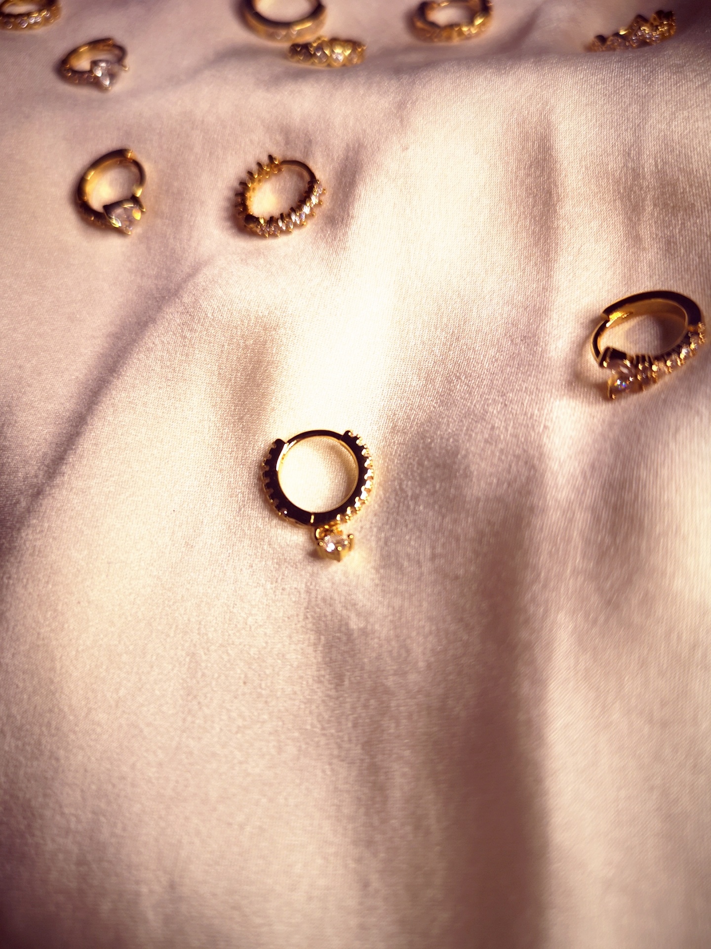 Brincos dourados pequenos sobre tecido branco