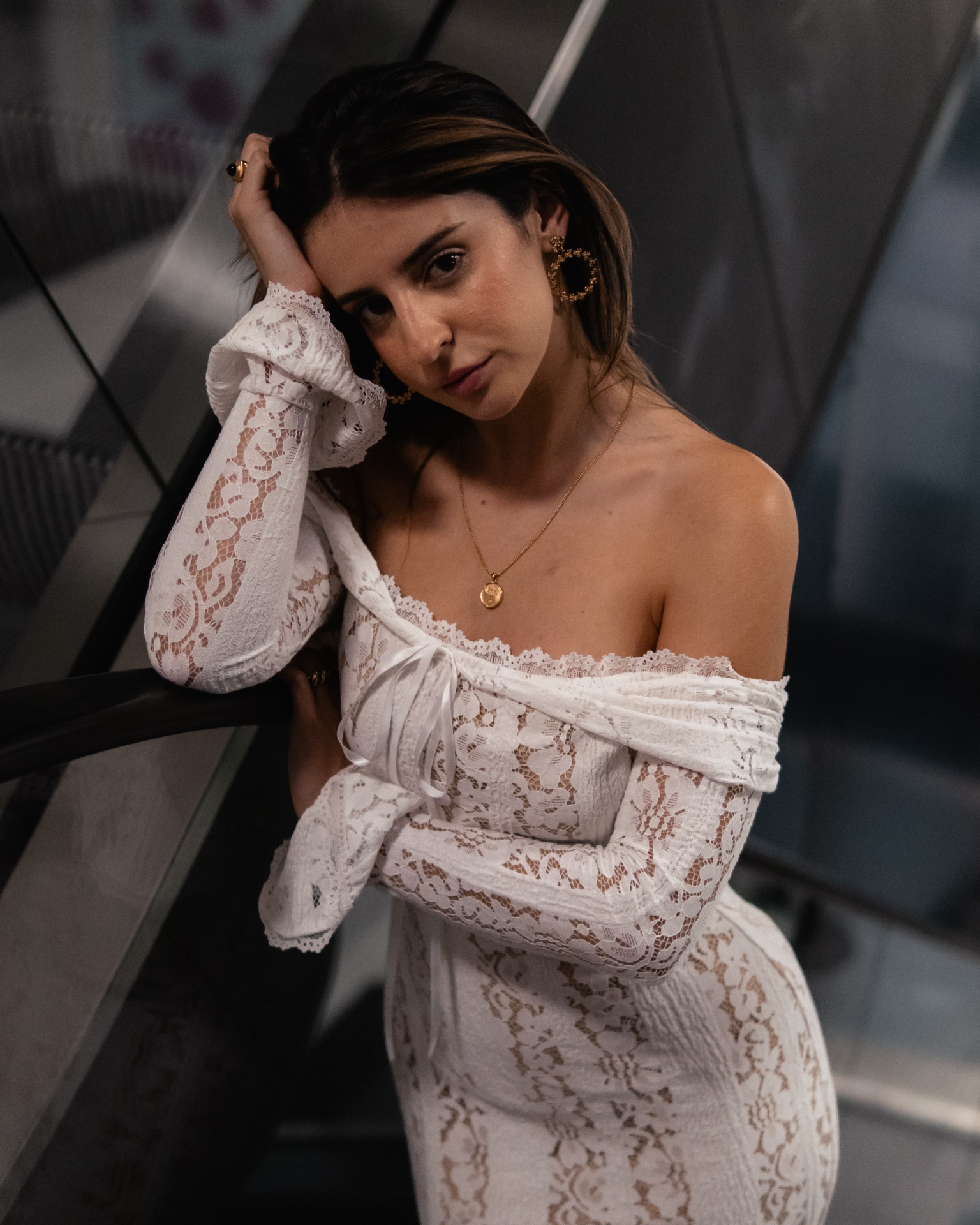 Mulher com vestido branco de renda ombro a ombro em ambiente interior moderno