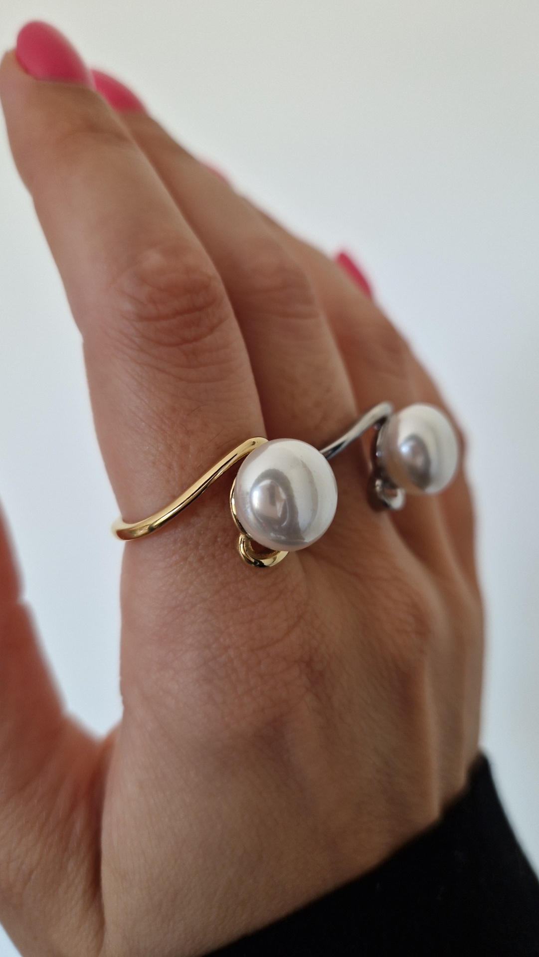 Anéis abertos com pérola em metal dourado e prateado numa mão