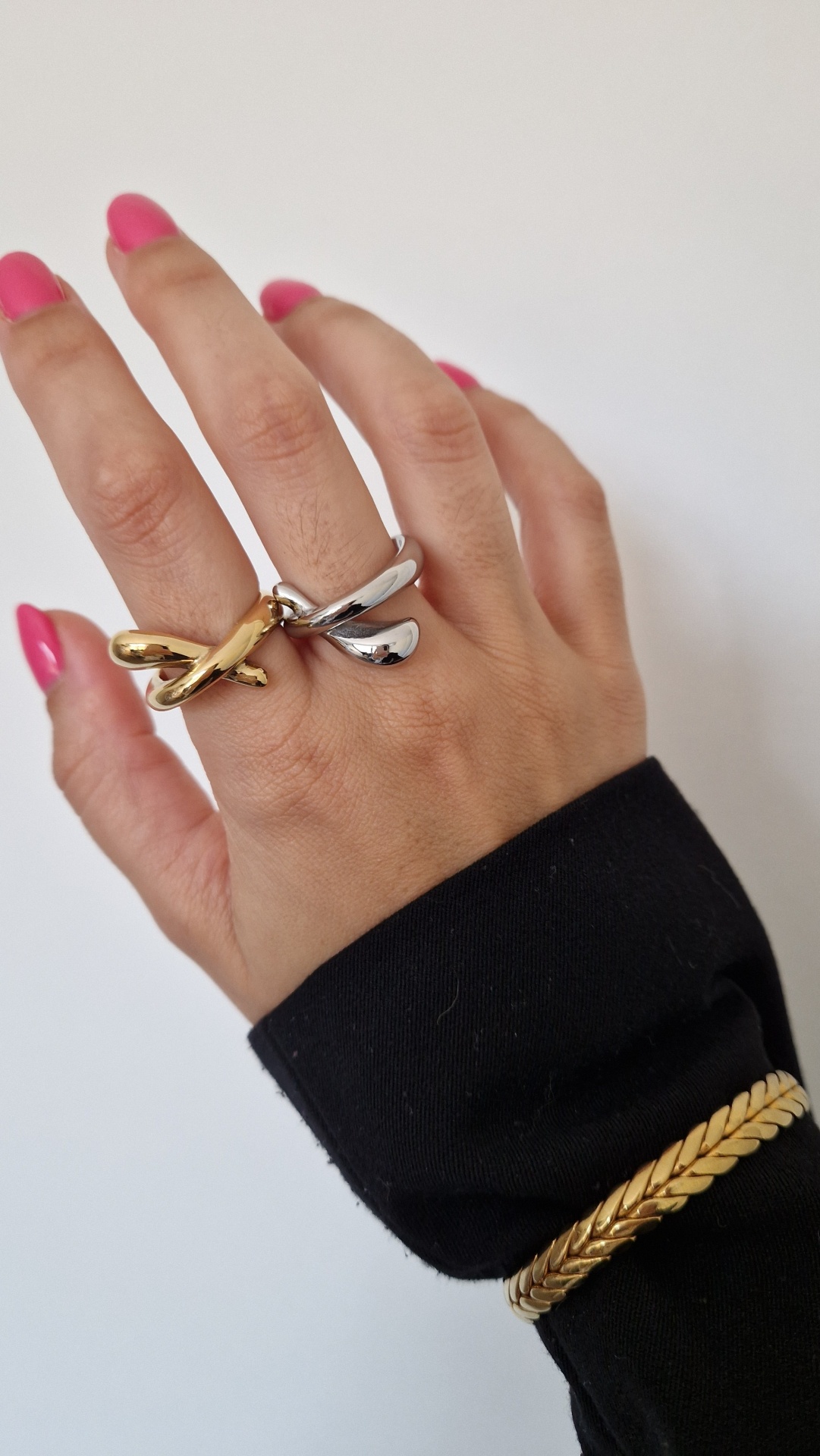 Mão com anéis dourado e prateado e pulseira dourada