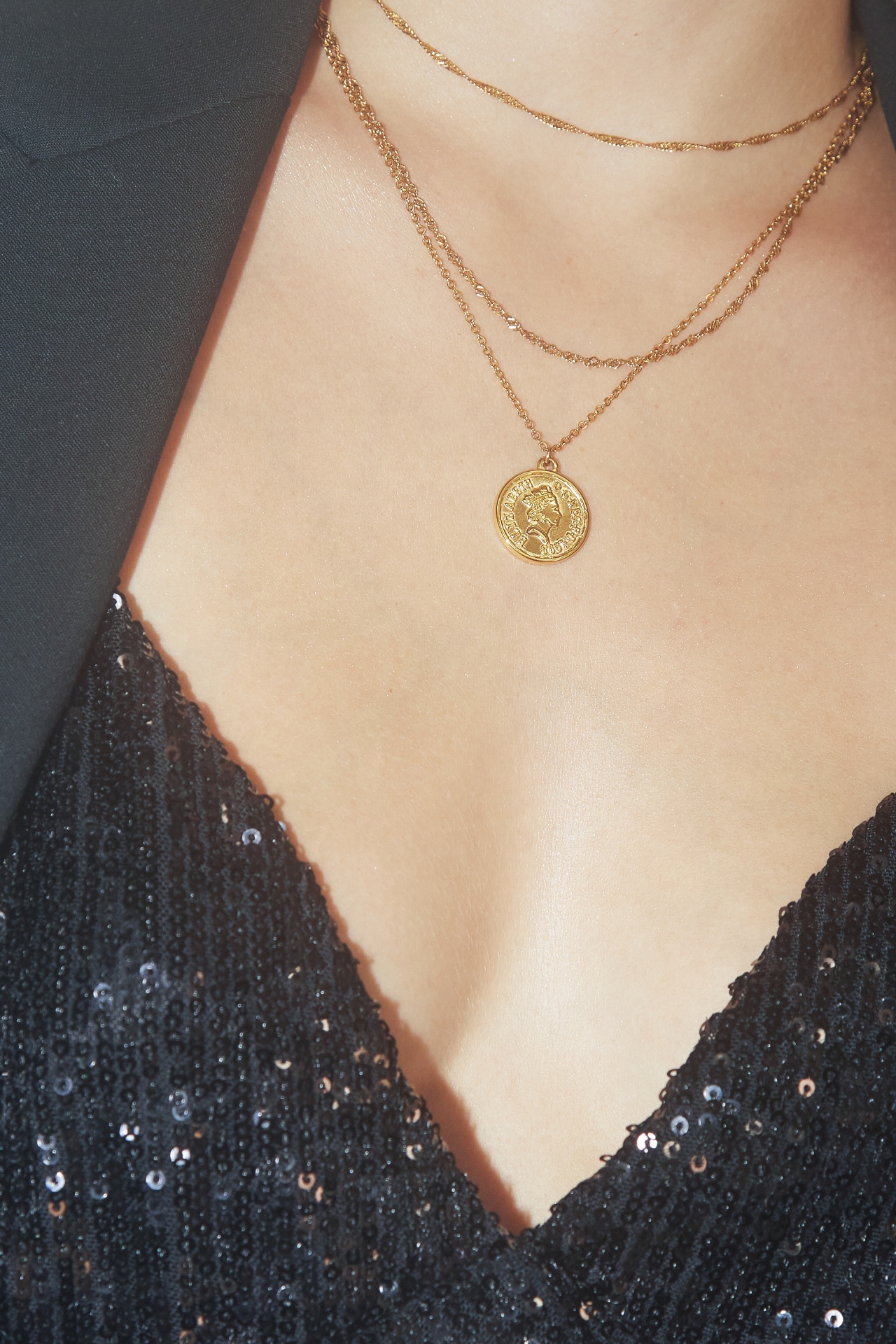 Decote com vestido preto de lantejoulas e colares dourados com pendente redondo