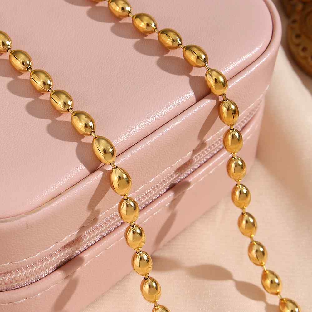 Colar de contas douradas sobre estojo rosa claro