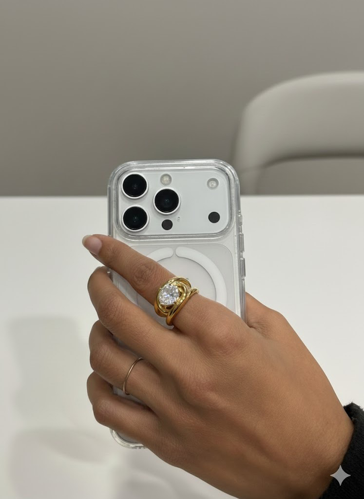 Telemóvel branco com capa transparente e mão com anéis dourado e prateado