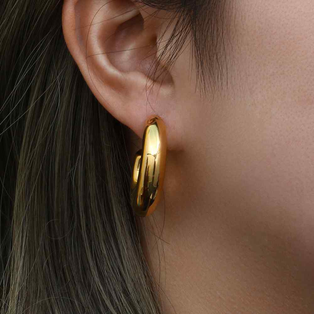 Brinco de argola dourada na orelha de uma pessoa