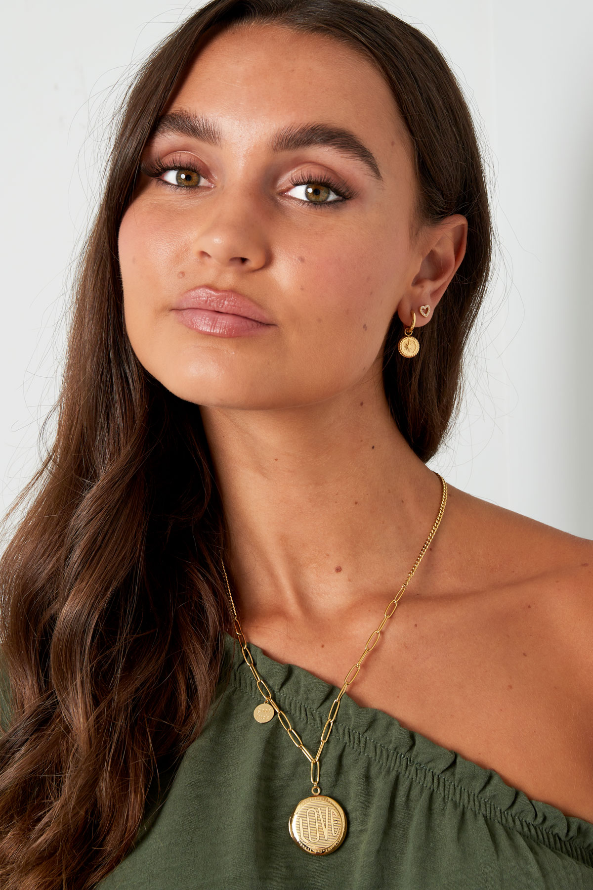 Mulher com colar e brincos dourados e blusa verde