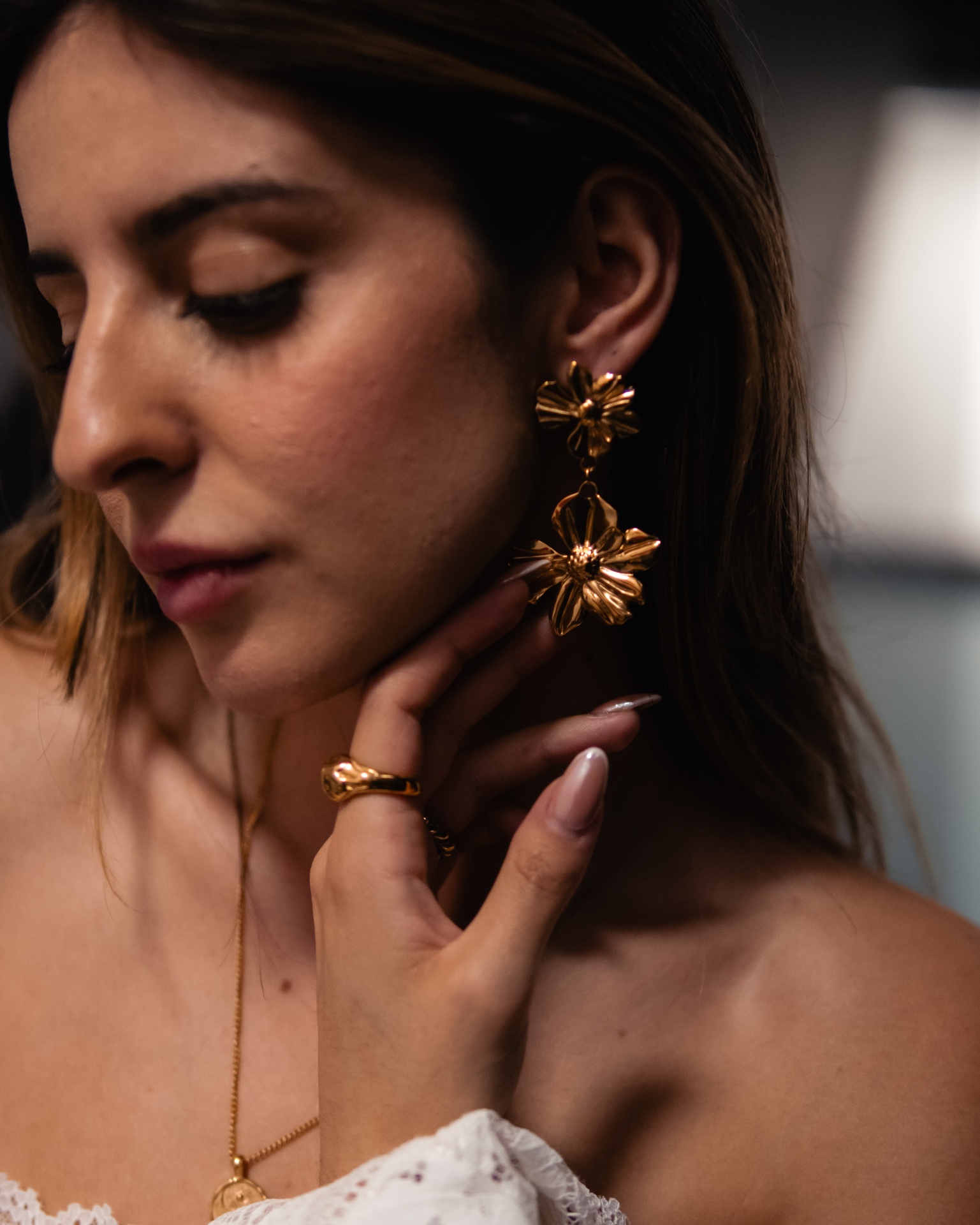 Mulher a usar brincos dourados grandes e anel dourado