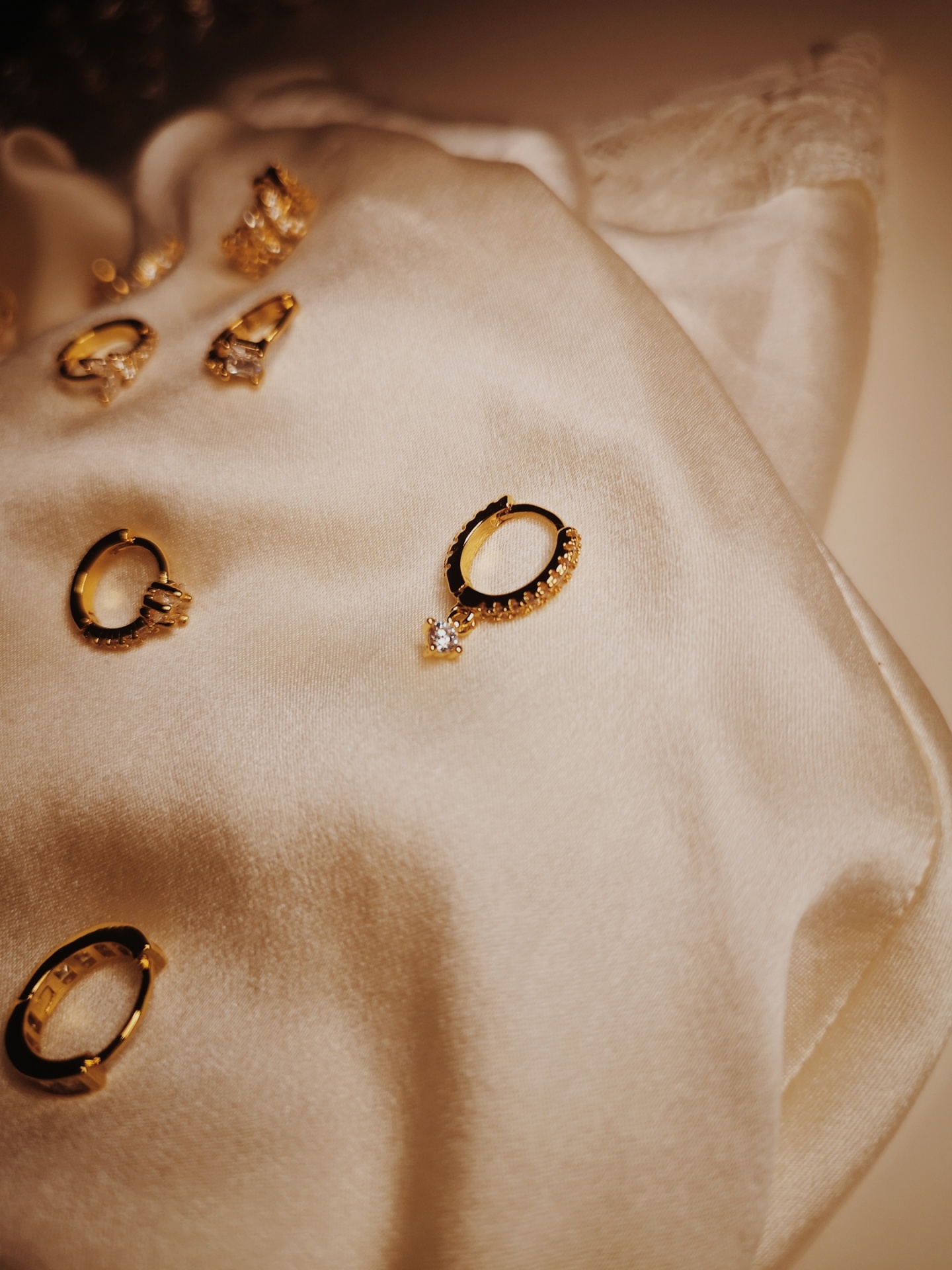 Joias douradas com pedras brilhantes sobre tecido de seda creme