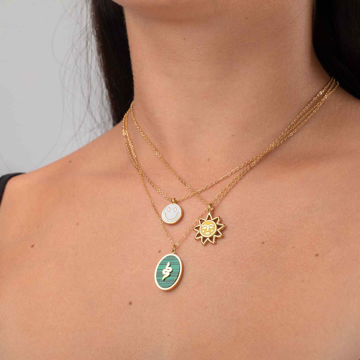 Colar feminino dourado com três pendentes diferentes usados no pescoço