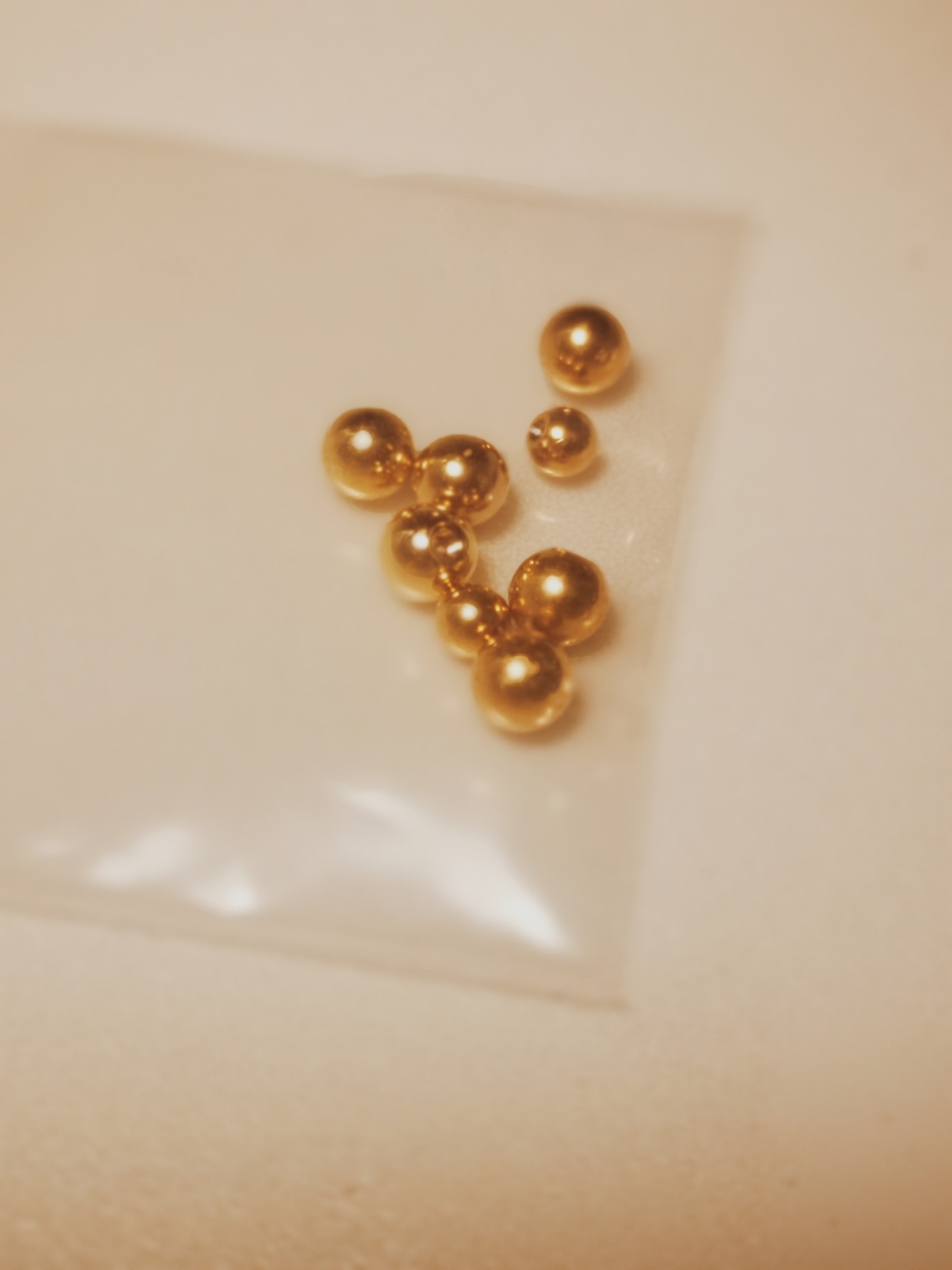 Pequenas bolas metálicas douradas num saco plástico transparente