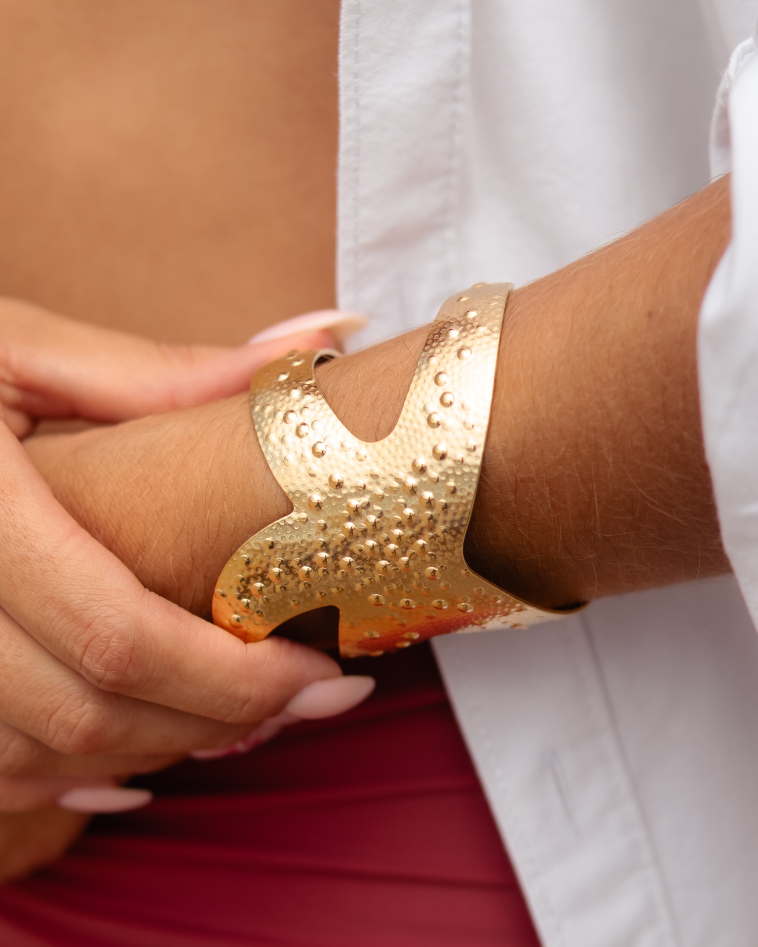 Pulseira dourada texturizada num pulso