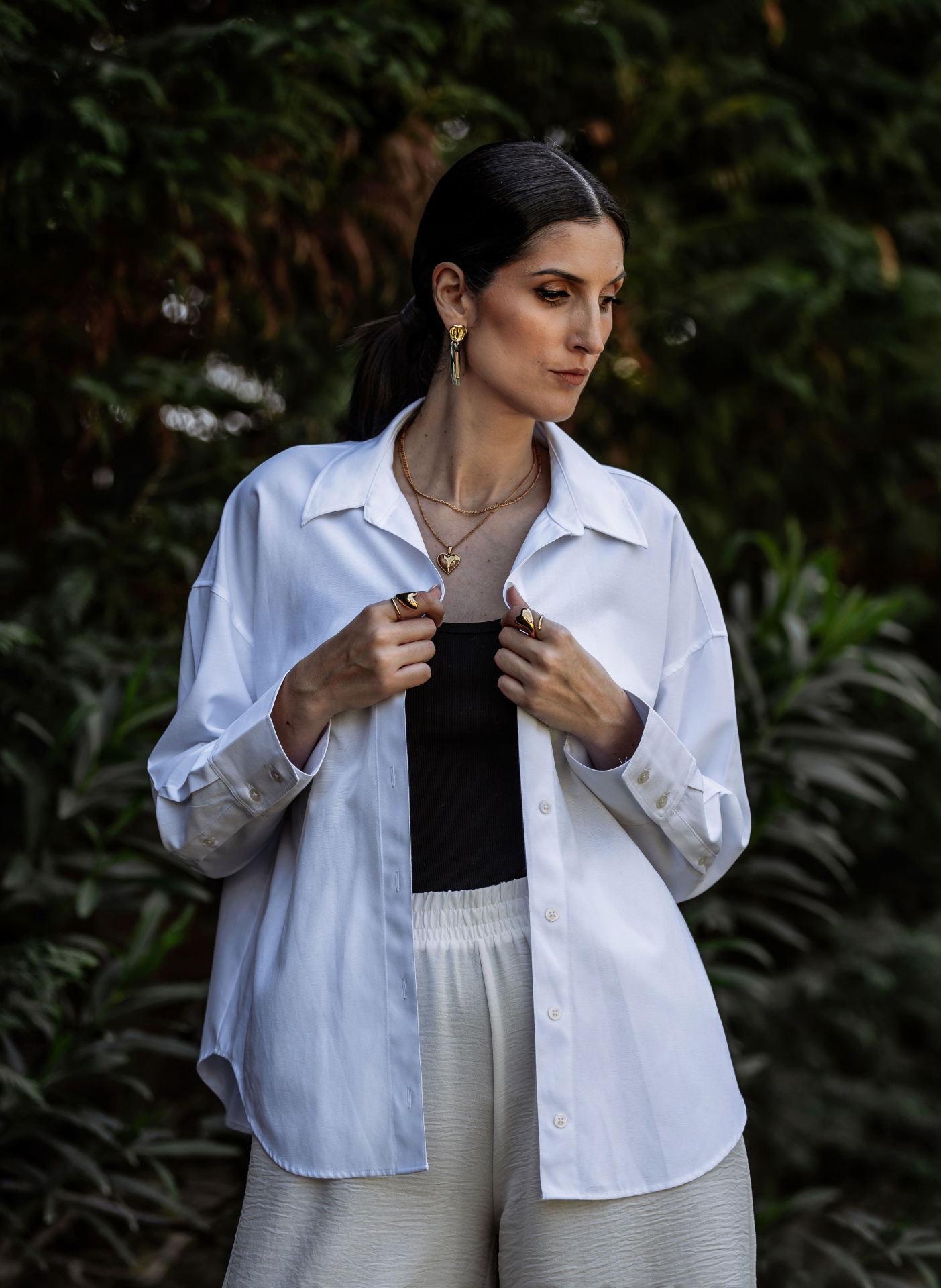 Modelo a usar camisa branca de algodão com botões e gola clássica, num jardim ou parque verde