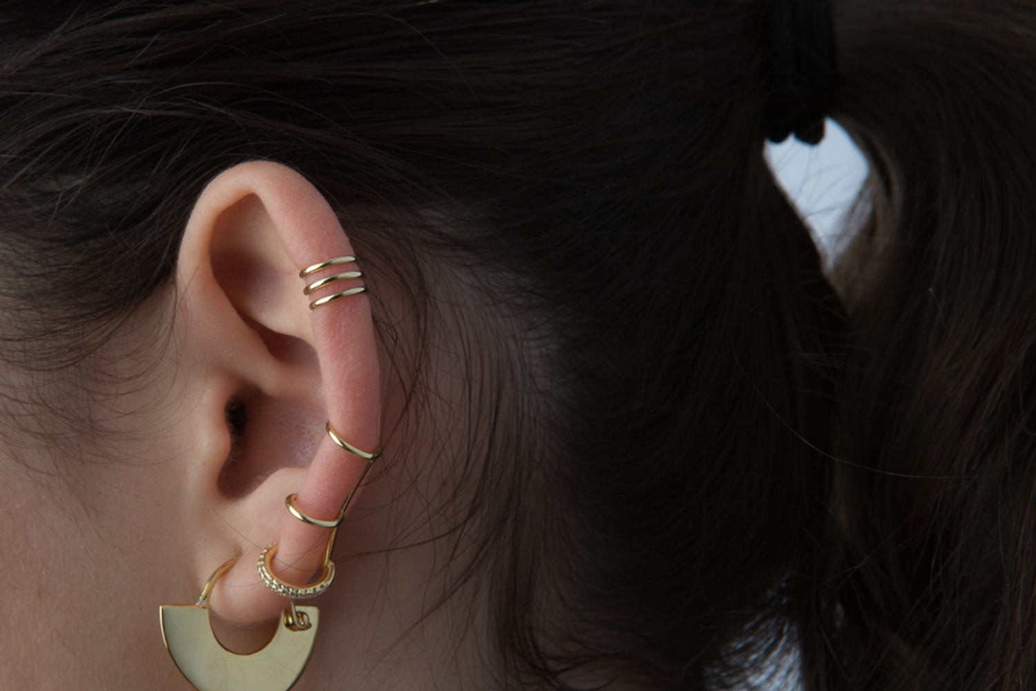 Orelha com brincos e argolas douradas variadas