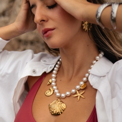 Mulher com colar de pérolas e pingentes dourados marinhos