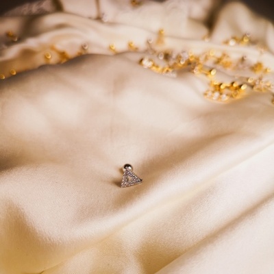 Brincos triangulares com pedras sobre tecido creme