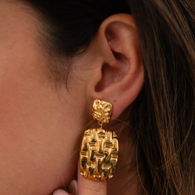 Brinco dourado texturizado com padrão geométrico em orelha