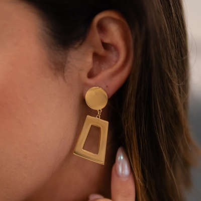 Brinco dourado pendente com base circular e trapezoidal recortado na orelha direita