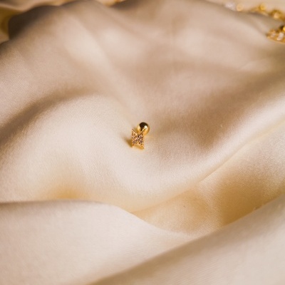 Brinco dourado pequeno sobre tecido creme