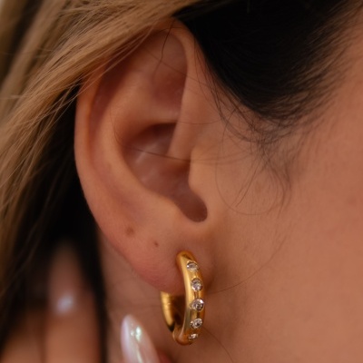 Brinco argola dourada com pedras brilhantes na orelha