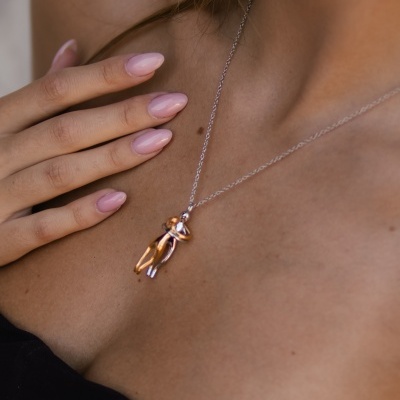 Colar com pendente metálico bicolor em prateado e dourado em mulher com roupa preta