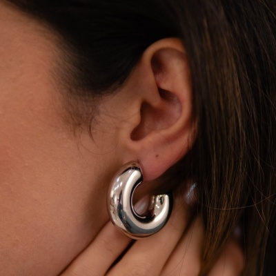 pendente argola grossa prateada num ouvido feminino