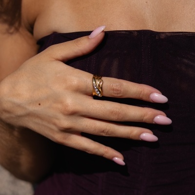 Mão feminina com anel dourado e pedras em vestido roxo