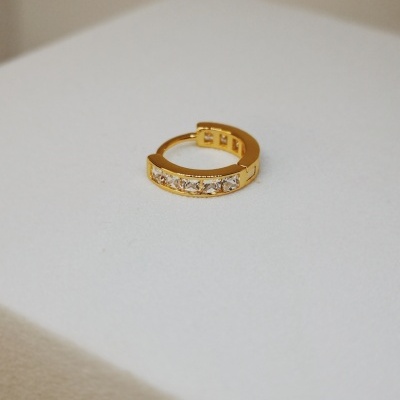 Argola dourada com pedras brilhantes sobre superfície branca