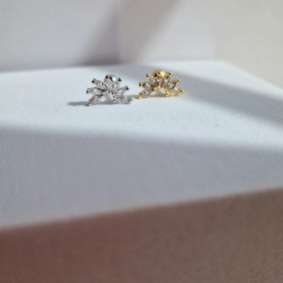 Brincos pequenos prateado e dourado com design de ramos e esferas sobre superfície branca