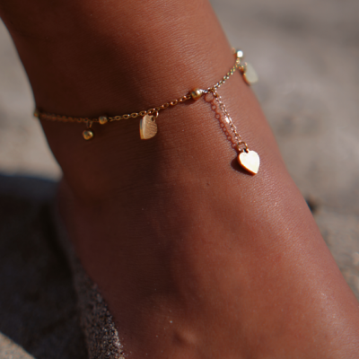 Torna tornozelo dourado com pendentes em forma de coração e círculo na areia