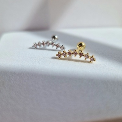 Brincos pequenos dourado e prateado com pedras transparentes em superfície branca