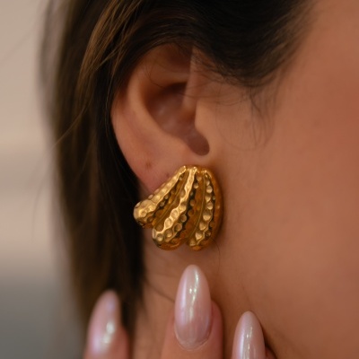 Brinco dourado texturizado tipo leque na orelha de mulher com unhas peroladas