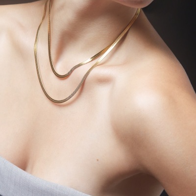 Colar duplo dourado em mulher com top cinza