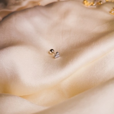 Brinco pequeno em forma de coração sobre tecido de seda creme