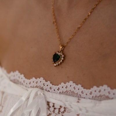 Colar dourado com pendente em gota verde e cristais em roupa branca de renda