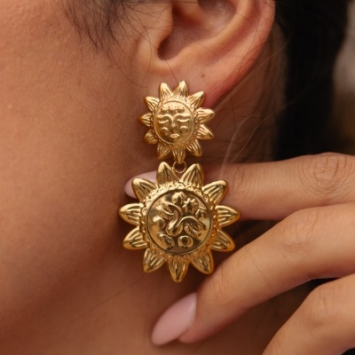 Brincos dourados em forma de sol com detalhes gravados