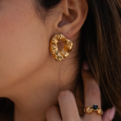 Brinco dourado de formato irregular e anel dourado com pedra preta em formato de coração