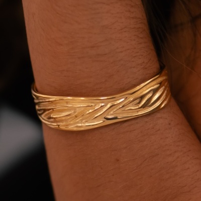 Bracelete dourado texturizado no pulso