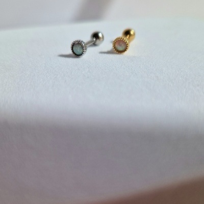 Dois brincos pequenos em metal prateado e dourado com pedras coloridas, sobre superfície branca