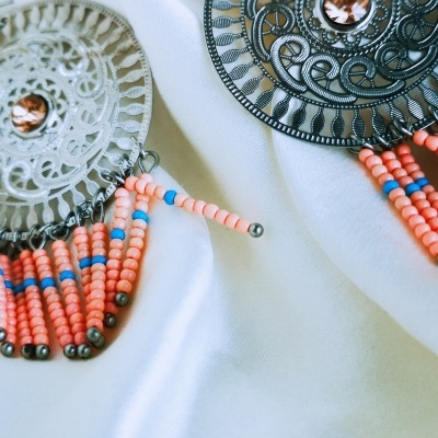 Brincos redondos de metal com contas cor-de-rosa e azul em fundo branco