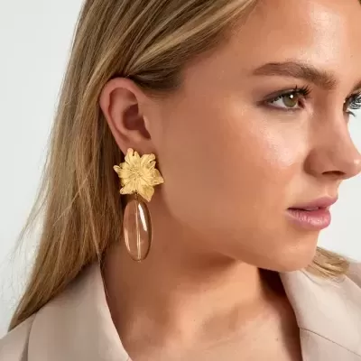 Brincos flor dourada com pendente oval castanho em mulher loira