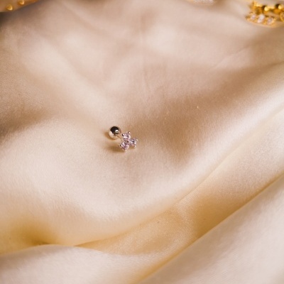 Brinco pequeno de flor com pedras sobre tecido de cetim bege