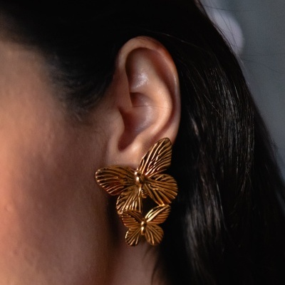 Brincos dourados com borboletas em orelha feminina