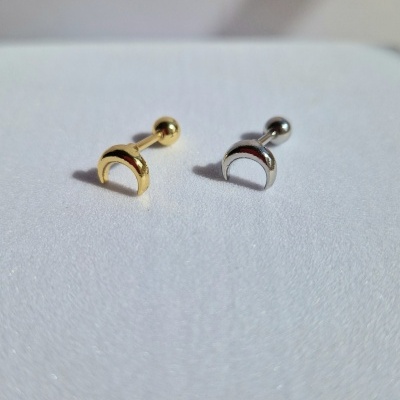 Dois piercings metálicos semicirculares, um dourado e um prateado, sobre fundo branco.
