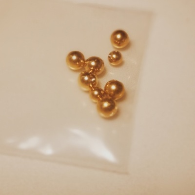 Pequenas bolas metálicas douradas num saco plástico transparente