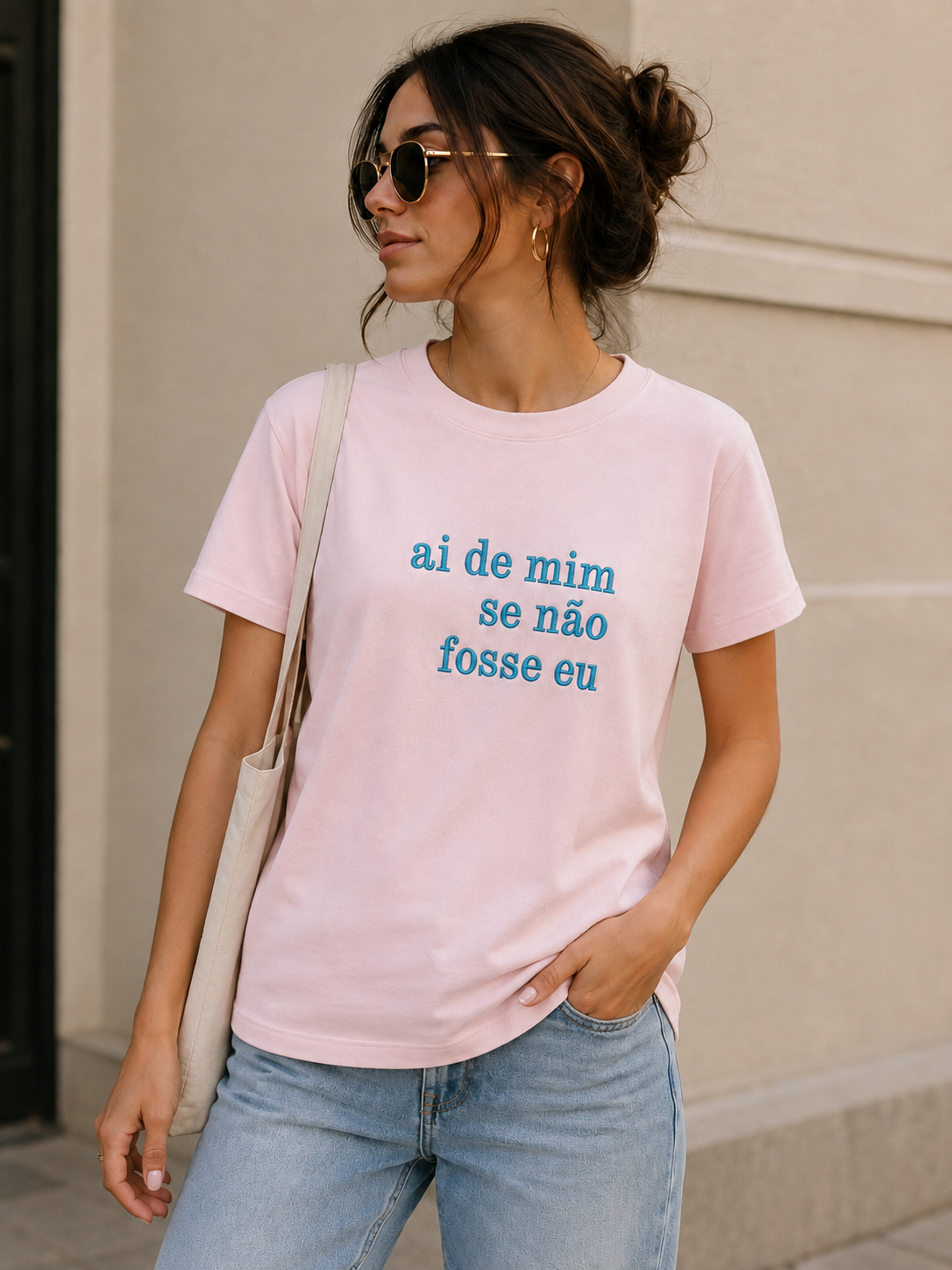 Mulher com t-shirt rosa e óculos escuros em ambiente urbano.