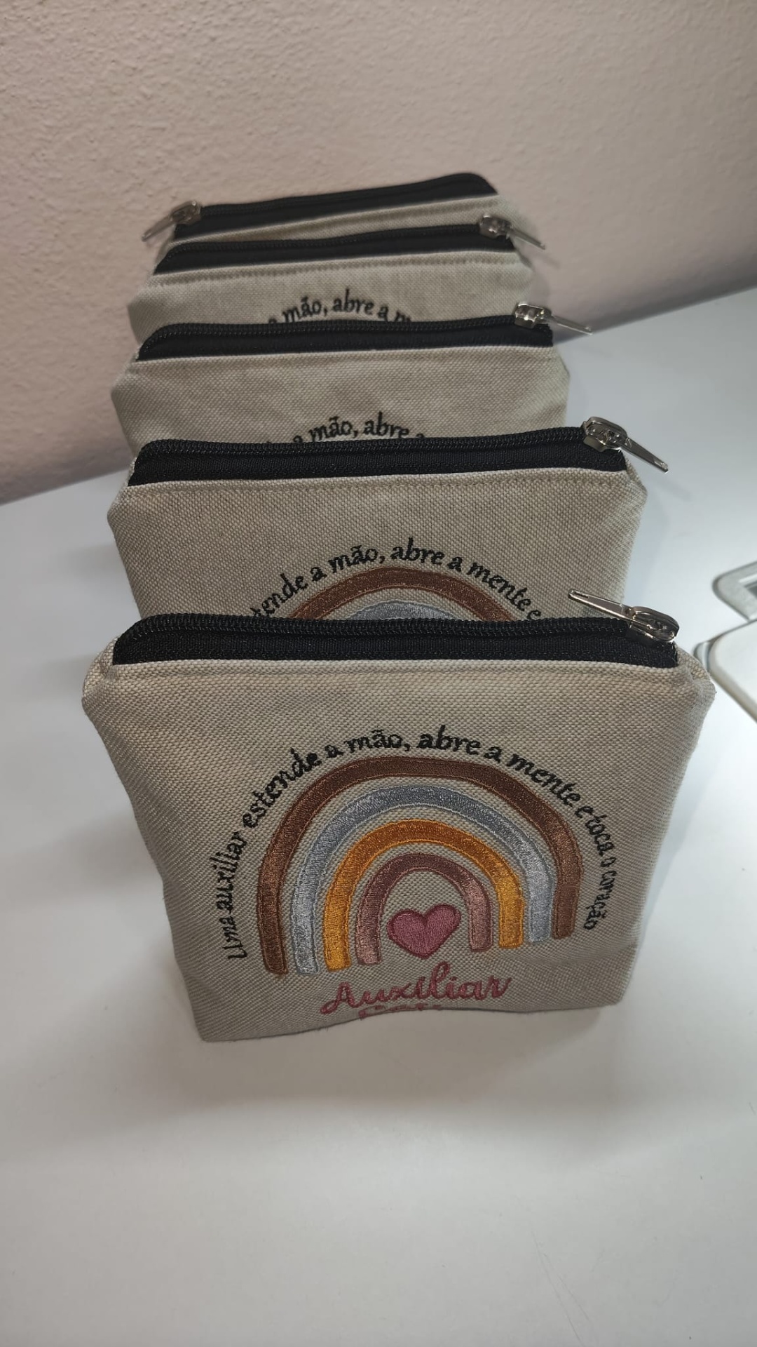 Conjunto de bolsas em tecido bege com fecho e bordados coloridos e texto em português